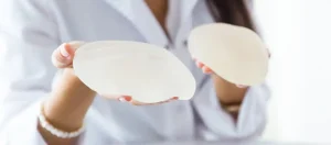 Sebész kétféle mellnagyobbító implantátumot tart a kezében a műtét előkészítése során.